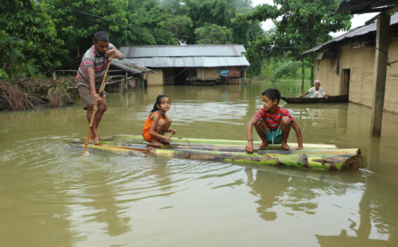 A man in Assam navigates his family to safety on a makeshift raft made of banana trunks. (Photo: Assam Times)